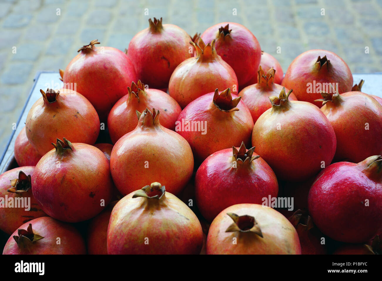 Piatto di rosa e rosso melagrane per la vendita su un mercato della frutta Foto Stock