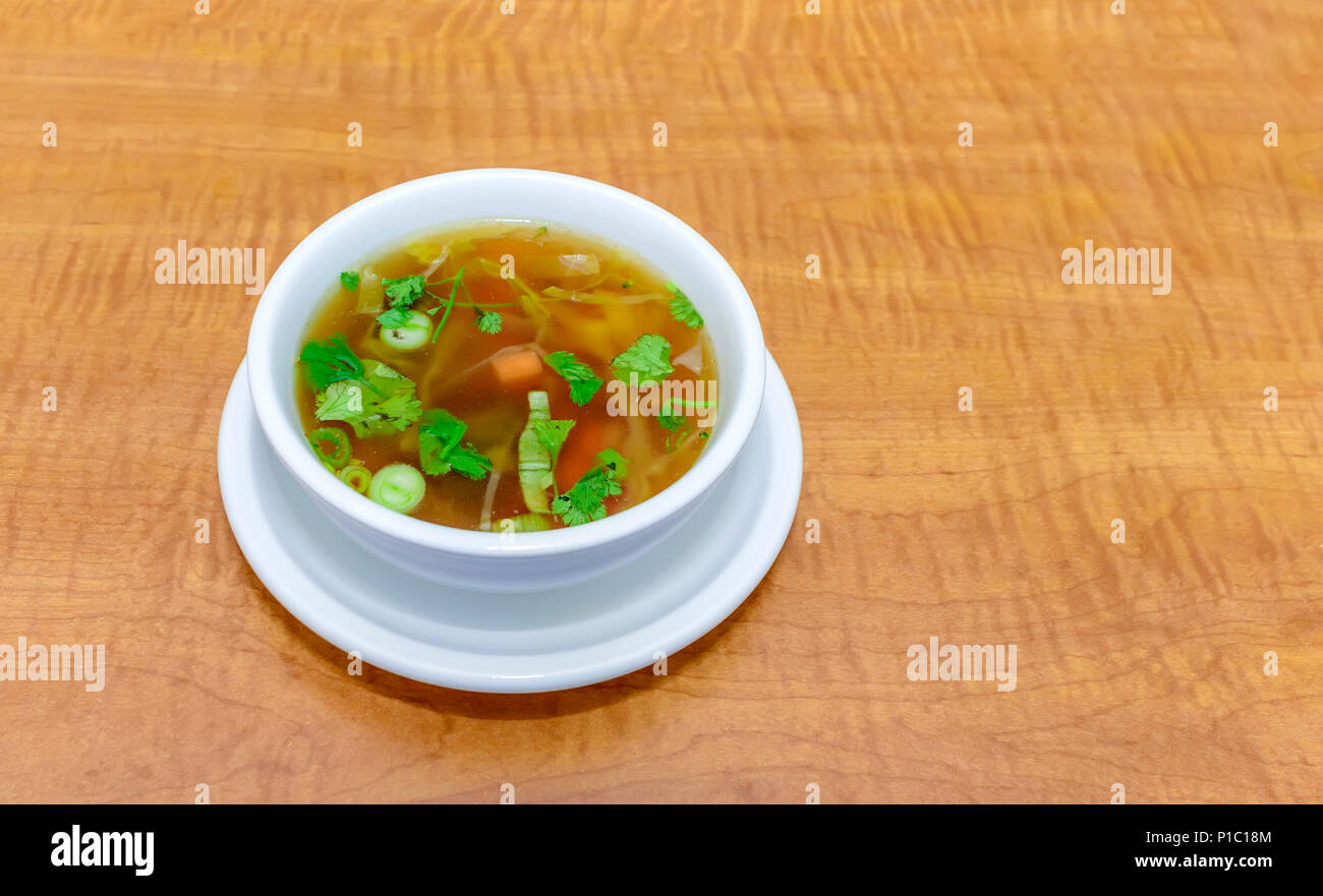 Vista dall'alto di una dieta deliziosa minestra di verdure con foglie di prezzemolo in porcellana bianca piastra su una tavola di legno Foto Stock