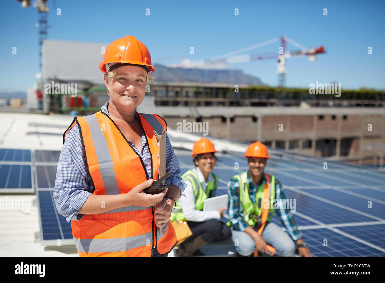 Ritratto sorridente e fiducioso ingegnere femmina con un walkie-talkie a sunny centrale solare Foto Stock