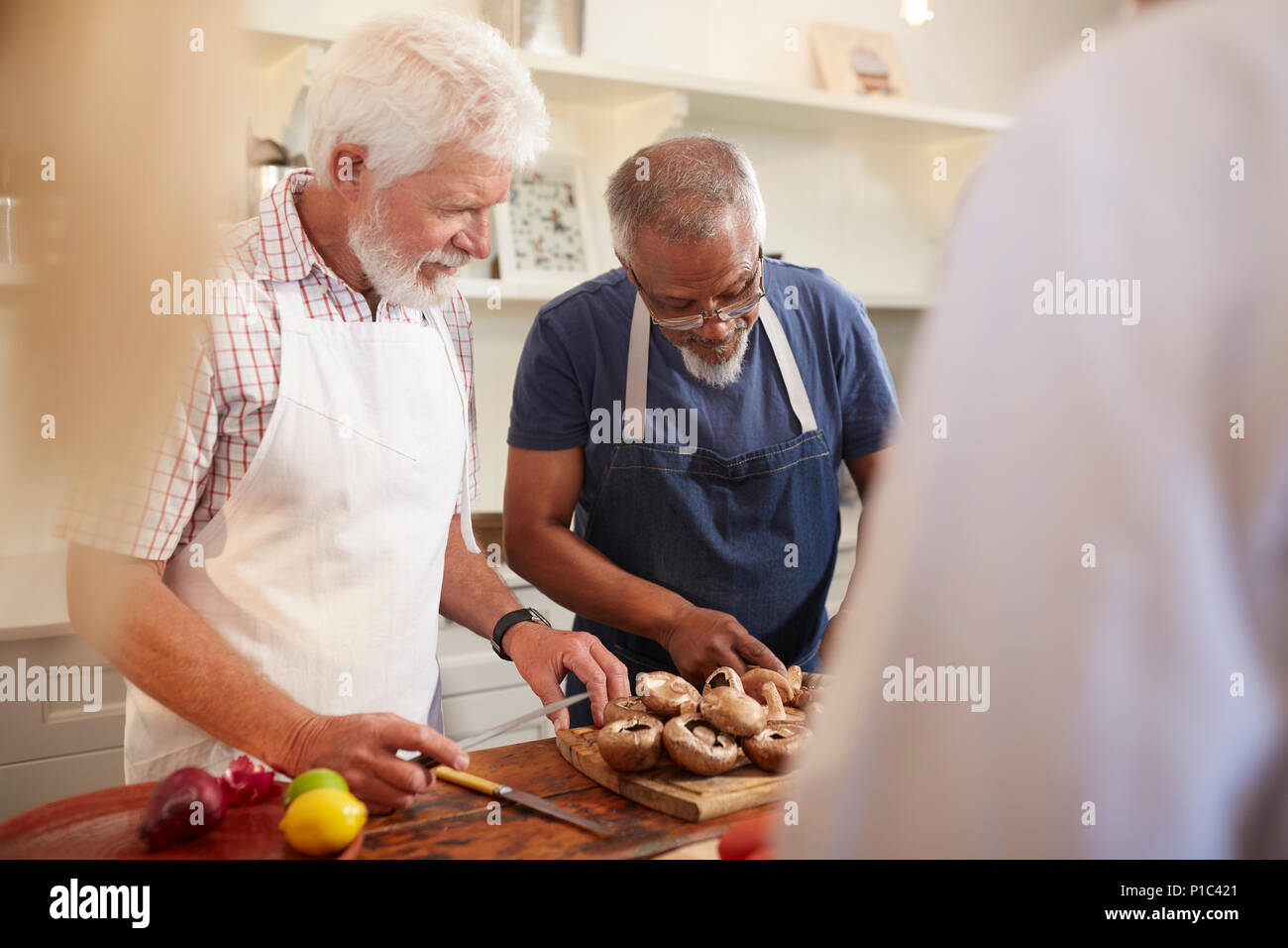 Alti uomini amici di funghi di taglio nella classe di cucina Foto Stock