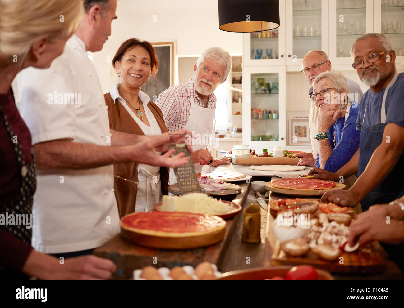 Senior amici ascolto di chef in pizza Cooking class Foto Stock