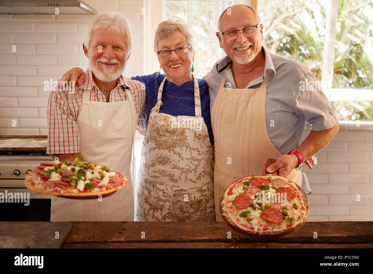 Ritratto sorridente e fiducioso amici senior rendendo la pizza in classe di cucina Foto Stock