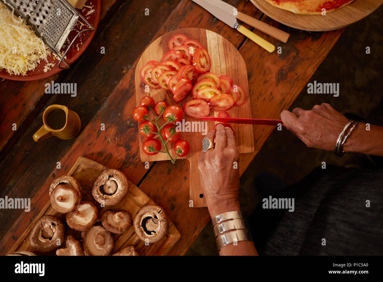 Vista aerea della donna per affettare i pomodori freschi per pizza Foto Stock