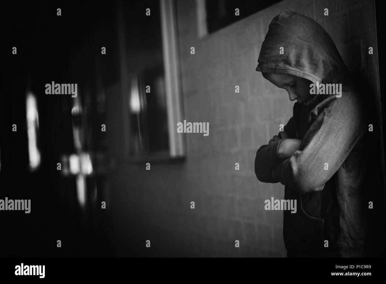 Ragazzo che sta da solo da parete in corridoio Foto Stock