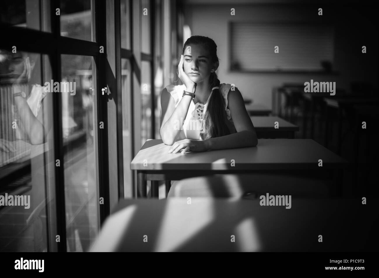Riflessivo schoolgirl seduta in aula Foto Stock