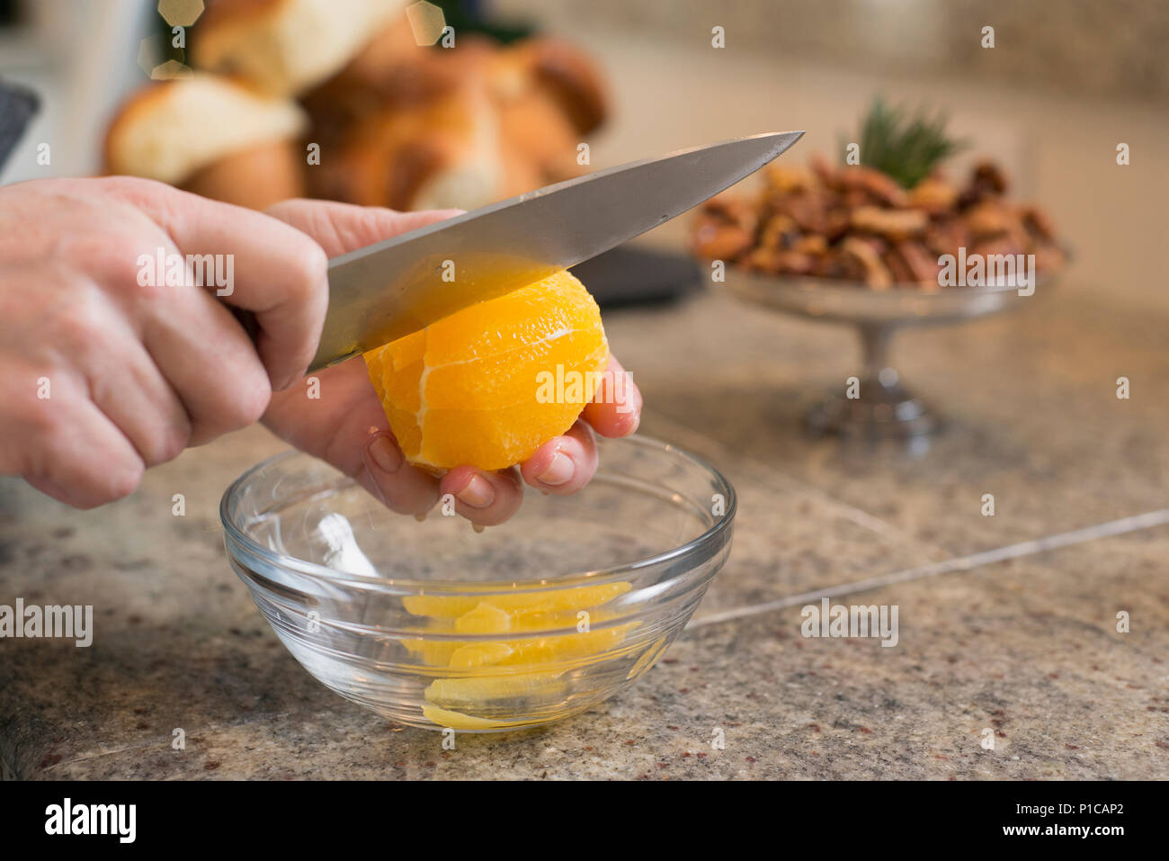 Una donna che prepara un arancione da utilizzare per un agrume che oltre a un'insalata. Foto Stock