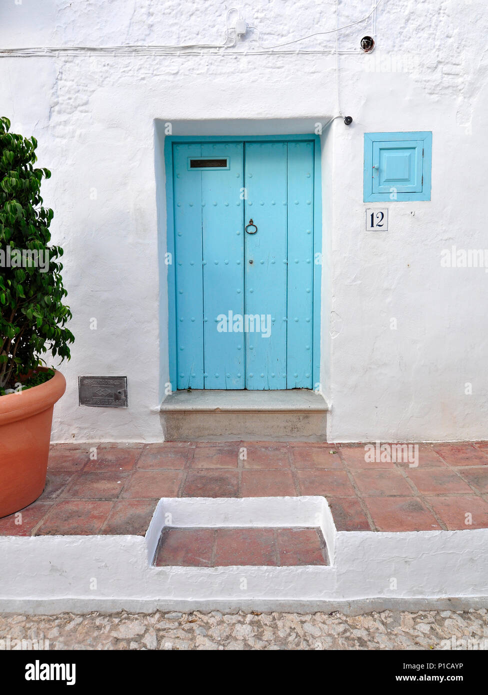 Un blu turchese porta in un dipinto di bianco villaggio andaluso nella Sierra de Tejeda. Foto Stock