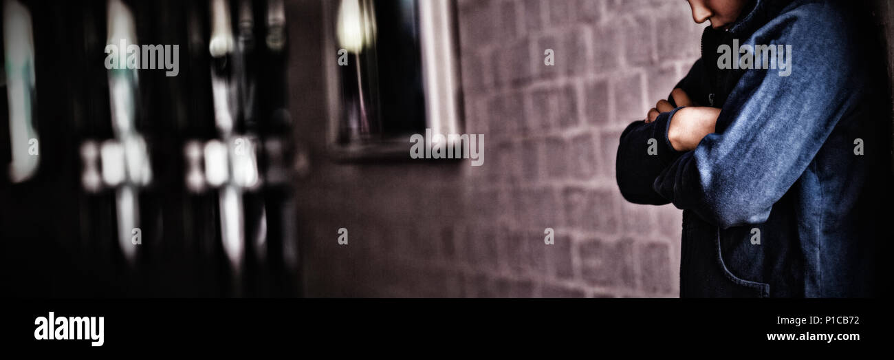 Ragazzo che sta da solo da parete in corridoio Foto Stock