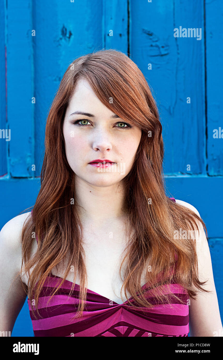 Un rosso donna dai capelli contro una parete di blu. Foto Stock