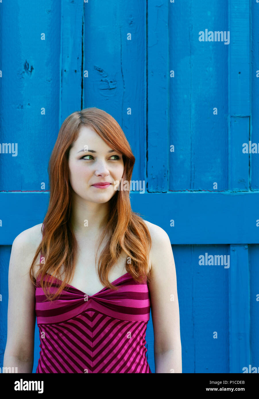Una giovane donna in piedi contro un muro di blu. Foto Stock