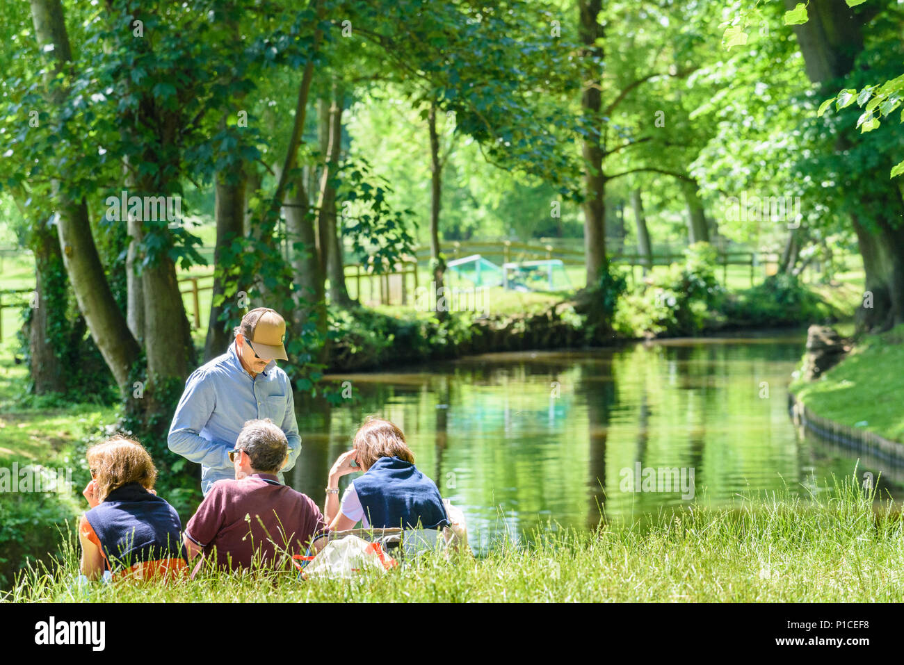Un gruppo di persone sedersi sulla riva del fiume Cherwell, Oxford, Inghilterra, su una soleggiata , giorno d'estate. Foto Stock
