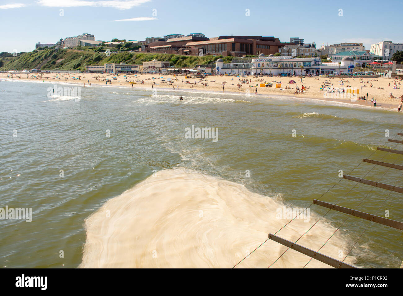 Le alghe marroni fioriscono più del solito all'inizio dell'estate al largo della costa meridionale. La fioritura delle alghe puzzolente, antiestetiche e spumose, vista qui a pooling sul mare sotto il molo, è considerata innocua per nuotatori e bagnanti. Bournemouth, Dorset, Inghilterra, Regno Unito, 11th giugno 2018. Foto Stock