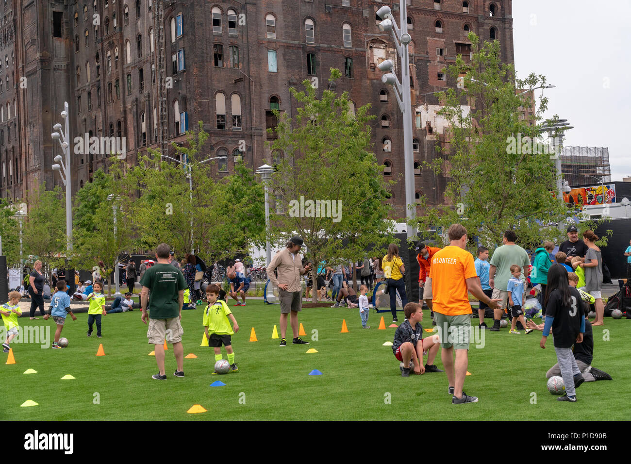 Nonostante il tempo inclemente di migliaia di visitatori accorsi per la grande apertura di Domino Parco nel quartiere di Williamsburg di Brooklyn a New York Domenica, 10 giugno 2018. Occupa il sito del Domino Sugar Co. raffineria, chiusa nel 2004, cinque acri di greenspace ha caratteristiche di acqua, scivoli, una passerella elevata, un Danny Meyer stand alimentari e pallavolo come pure molte altre dotazioni. Progettato da James Corner Field Operations, gli architetti dietro il design della linea alta, la raffineria di mattone di edificio, di cui una volta elaborato il 50 percento di tutto lo zucchero negli Stati uniti rimane per de Foto Stock