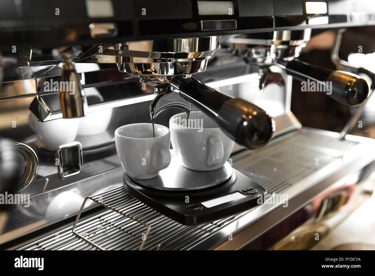 Caffè espresso italiano macchina su un contatore in un ristorante di erogazione di caffè appena fatto in due piccole coppe Foto Stock