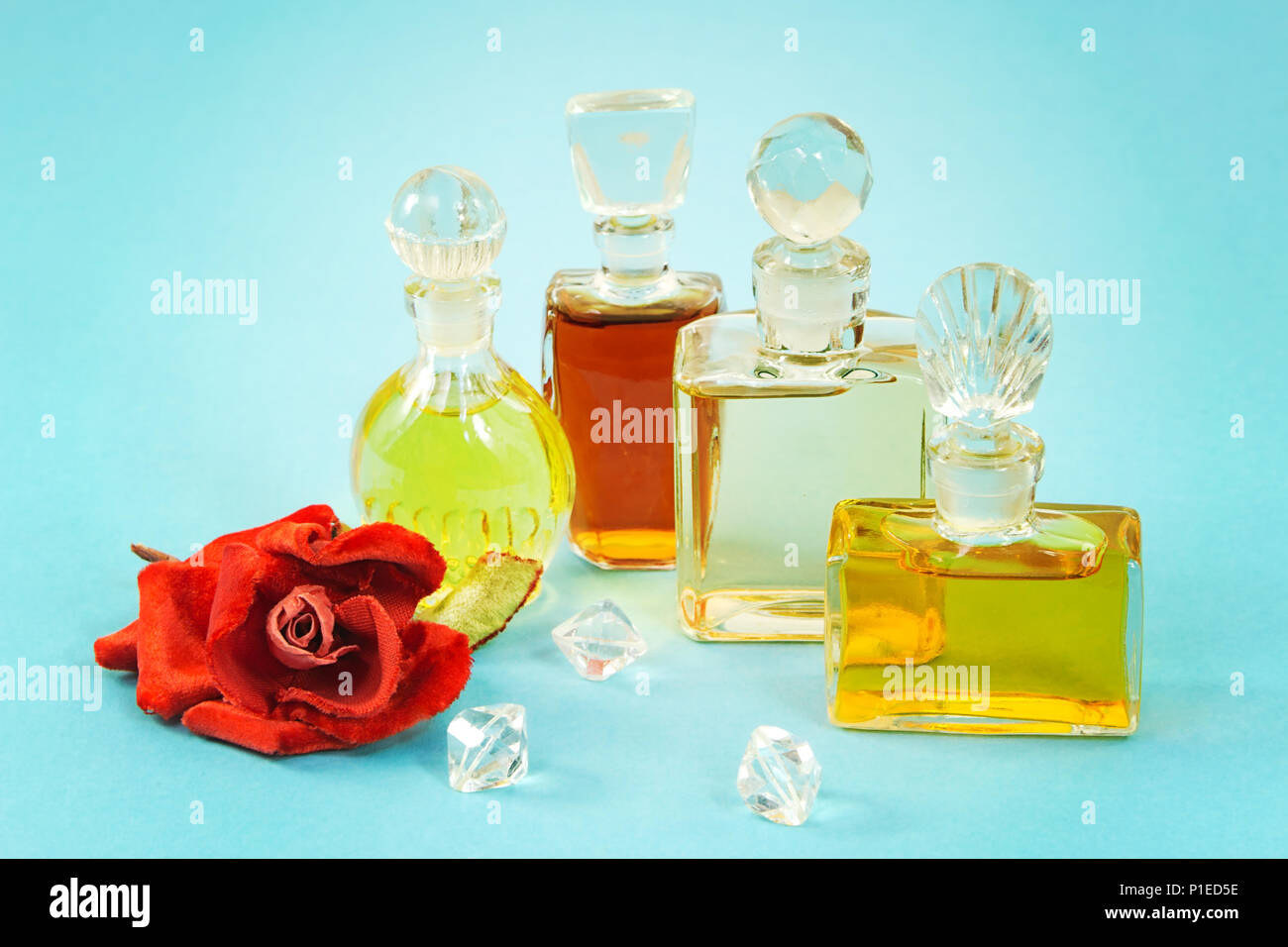 Vintage di bottiglie di profumo e peluche artificiale rosa rossa su blu Foto Stock