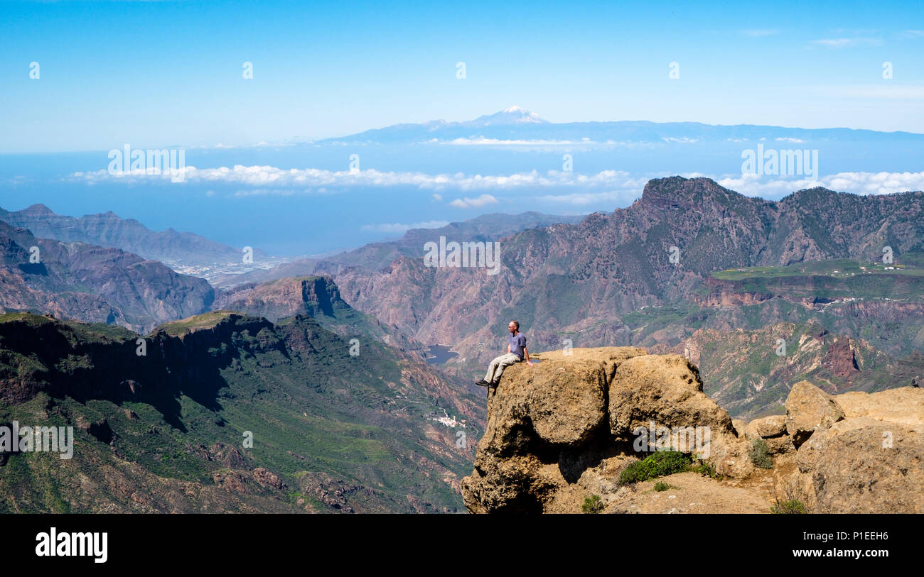 L'uomo guarda da Roque Nublo oltre il paese di montagna di Gran Canaria con il vulcano Teide All'orizzonte, Gran Canaria Isole Canarie Spagna Foto Stock