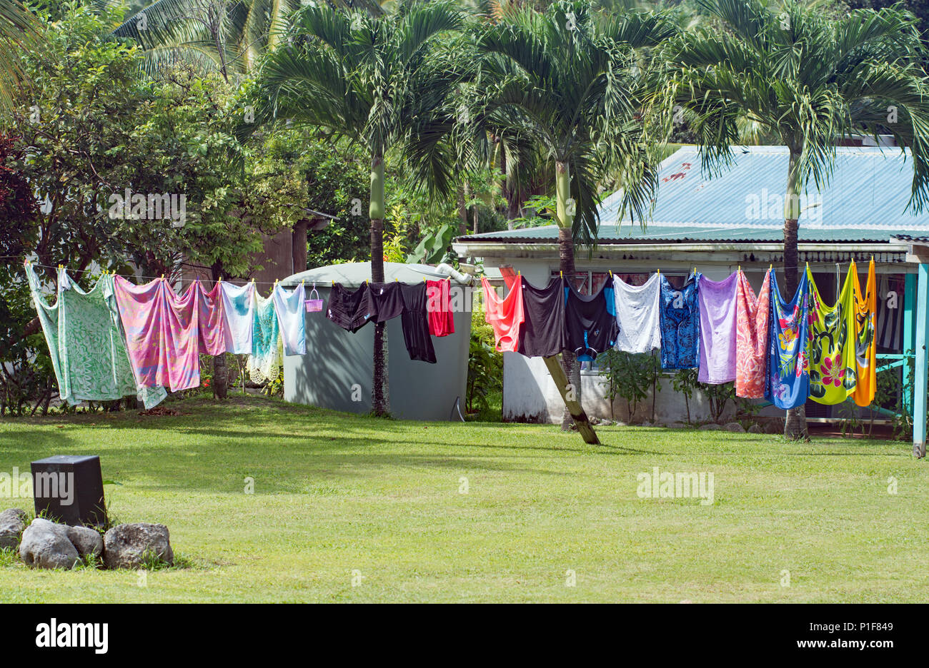 Lavaggio colorati appesi ad asciugare su una lunga linea di abbigliamento in Aitutaki Foto Stock