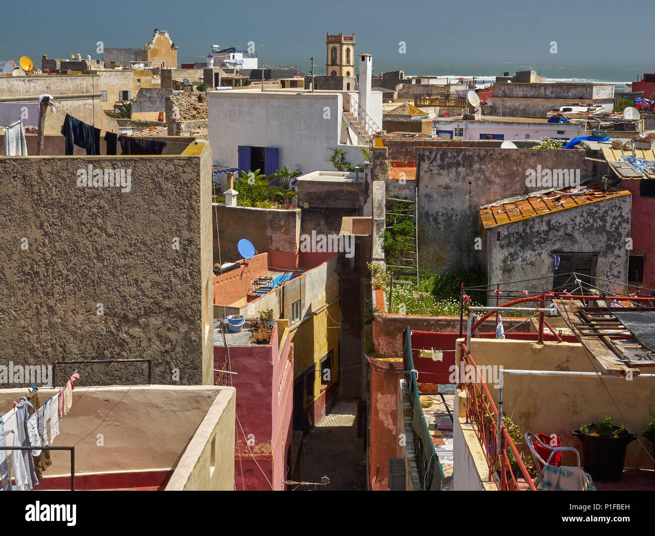 Tetti di edifici antichi della medina di El Jadida città: alte mura, corda con abiti appesi, cielo blu, Marocco. Foto Stock