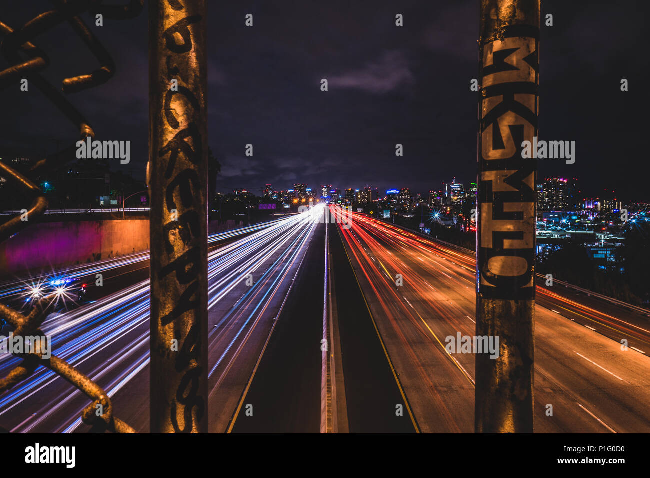 Il traffico della città di notte attraverso una recinzione Foto Stock