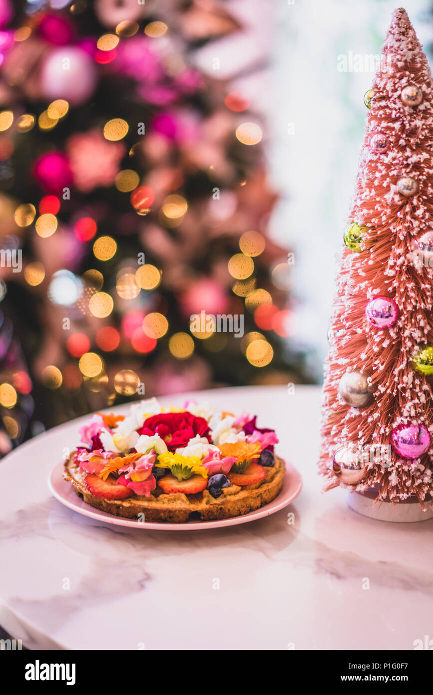 Waffle con frutta e fiori su un tavolo con colorate decorazioni di Natale Foto Stock