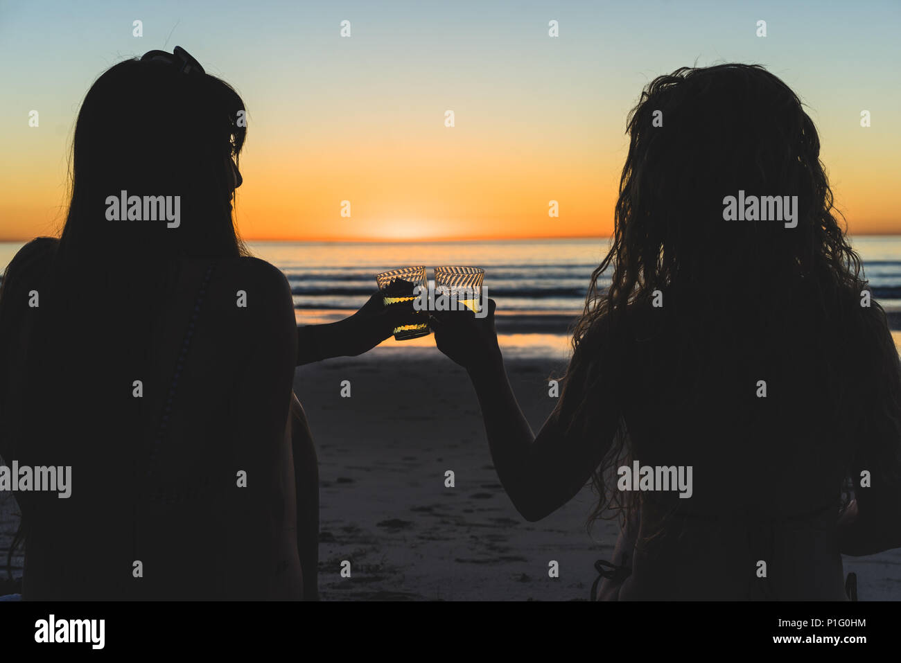 Silhouette di amici bevendo vino sulla spiaggia al tramonto Foto Stock