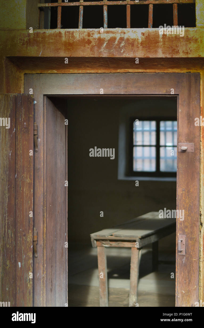 Haunting immagine di una cella a Terezin Theresienstadt () Concentrazione Camp con luce tenue attraverso una finestra sbarrata evidenziando uno sgabello. Foto Stock