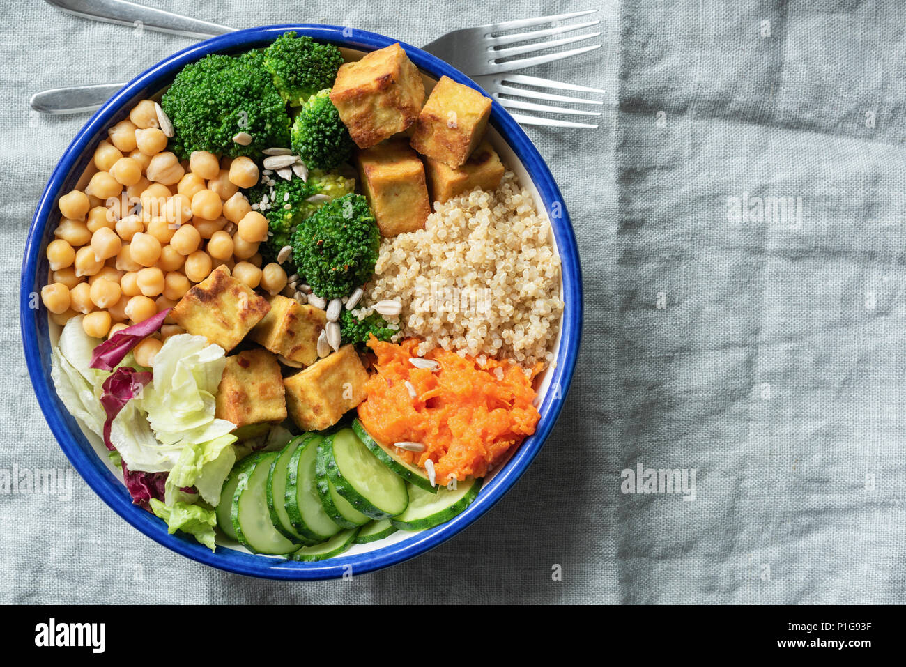 Insalatiera con la quinoa, tofu, i ceci e le verdure su lino tessile. sfondo Vista superiore, copia spazio per il testo Foto Stock