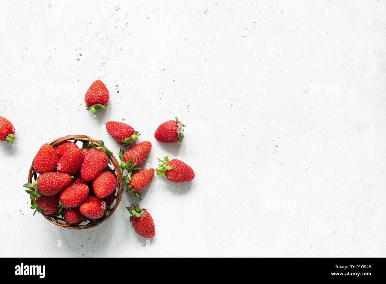 Fragole fresche nella ciotola sul grigio brillante background in calcestruzzo. Le fragole in un recipiente. Vista dall'alto di carni succose fragole Foto Stock