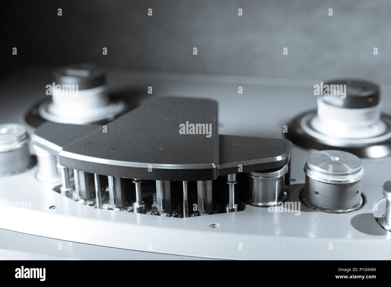 Macro close up vintage professionale multitraccia analogica di un pollice studio registratore a nastro, lo stelo e la testa uno sfondo grigio Foto Stock