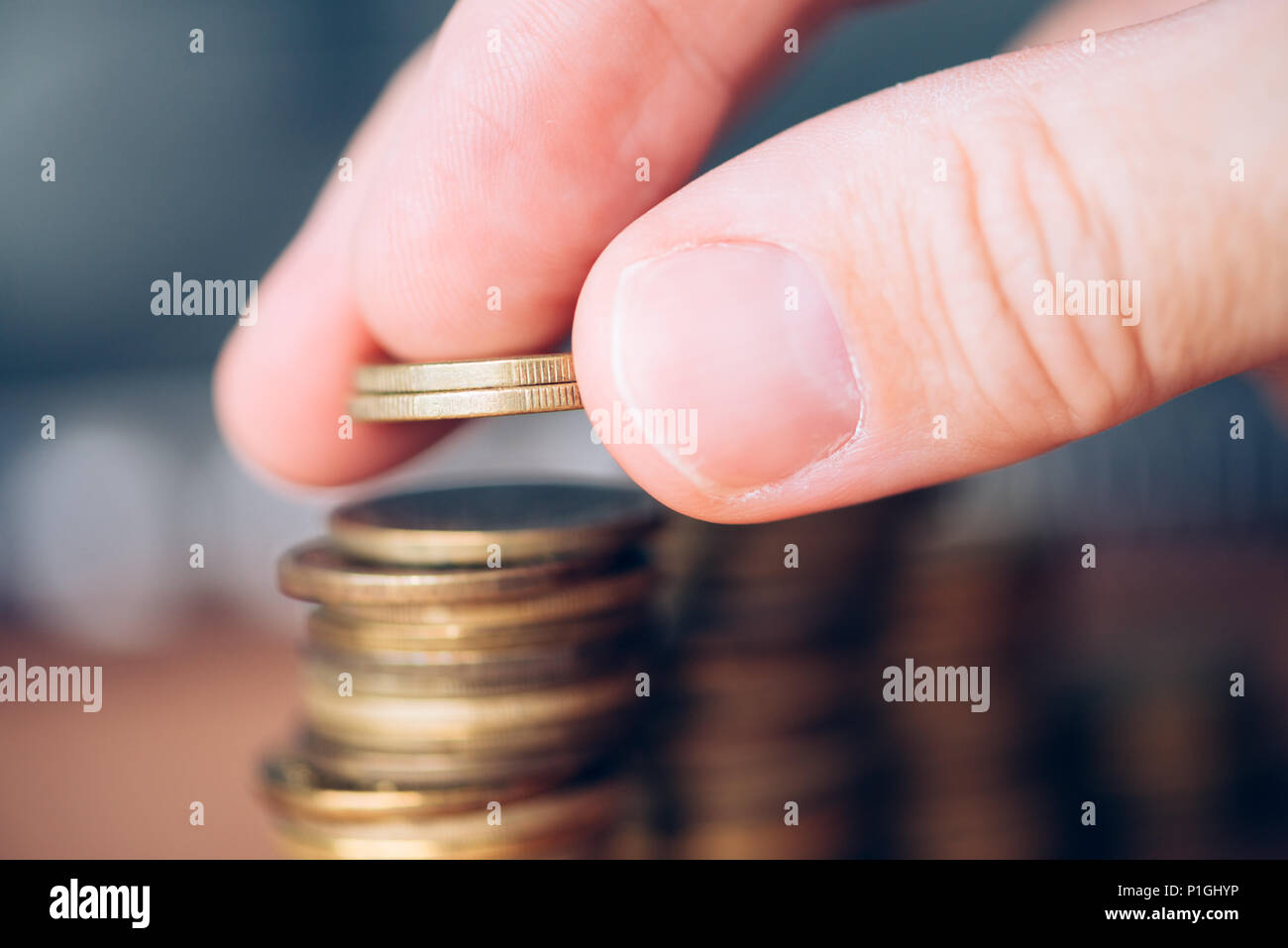 Stretta di mano maschio monete di impilamento. Risparmio di denaro e di concetto di budget. Foto Stock