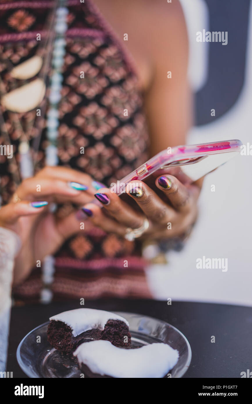 Primo piano della donna nera usando un telefono cellulare con una bella manicure Foto Stock