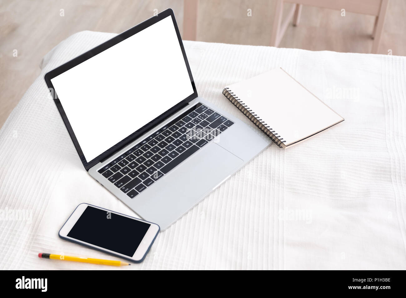 Mock up schermo bianco del laptop con il telefono cellulare e il PC  portatile in bianco sulla coperta del letto in camera da letto.il lavoro a  casa concetto.copia spazio per aggiunta di