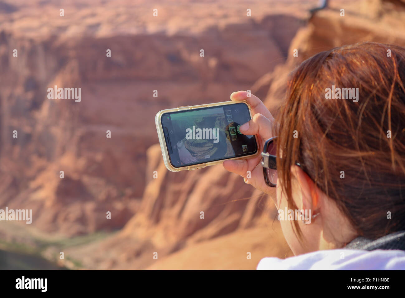 Smart phone view della curva a ferro di cavallo in Arizona. Ragazza giovane donna, scattare una foto con il suo iPhone della mitica linea curva a ferro di cavallo. Foto Stock