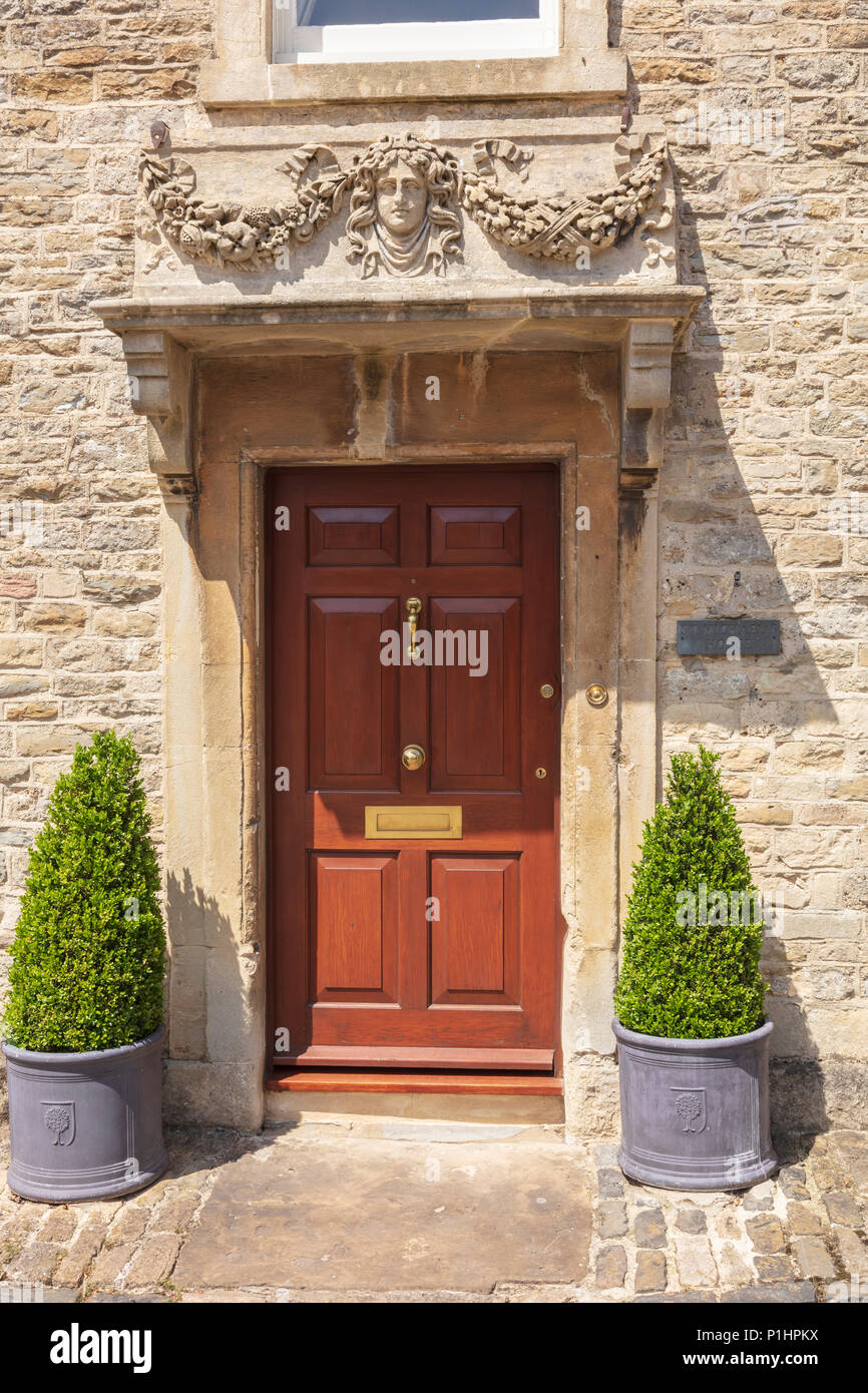 St Michael's House, un attraente cotswold casa in pietra con portico attraente e la casella alberi ogni lato della porta anteriore, Malmesbury, Wiltshire, Regno Unito Foto Stock