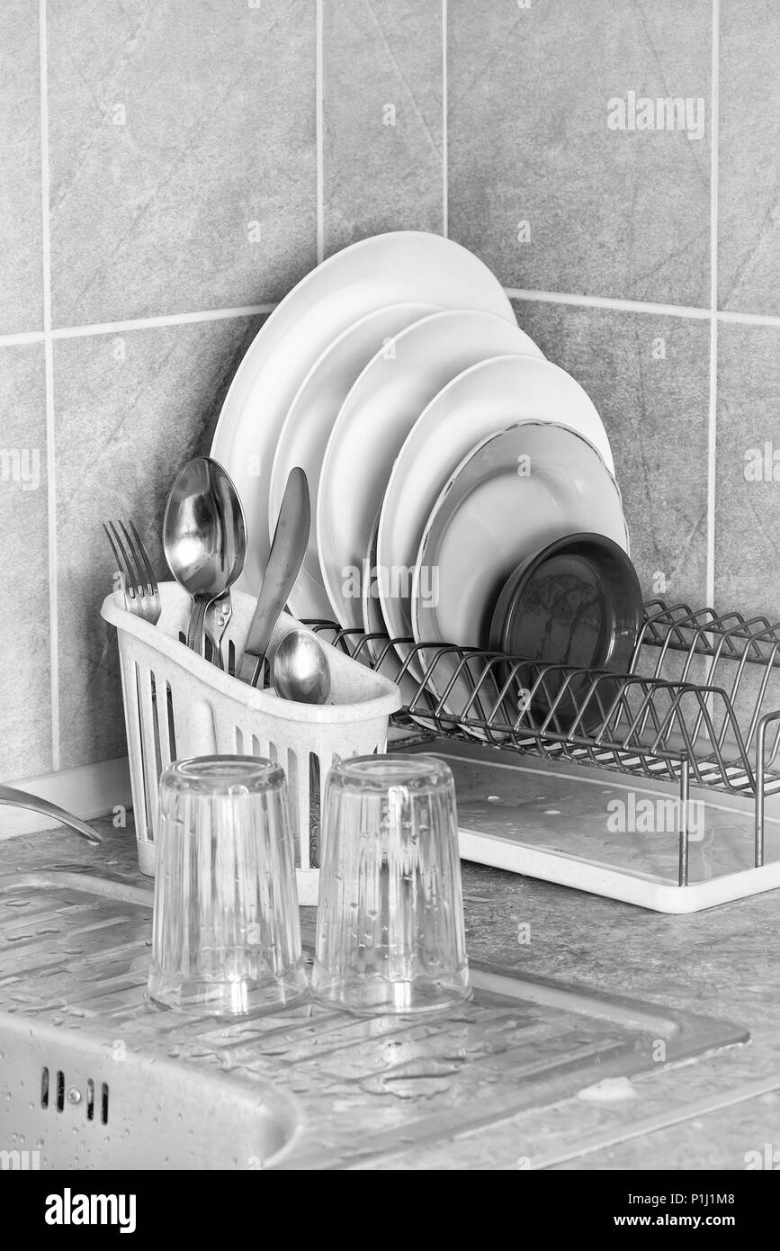 Lavare piatti, posate e bicchieri, essiccazione nel loro rastrelliere vicino al lavello in cucina Foto Stock