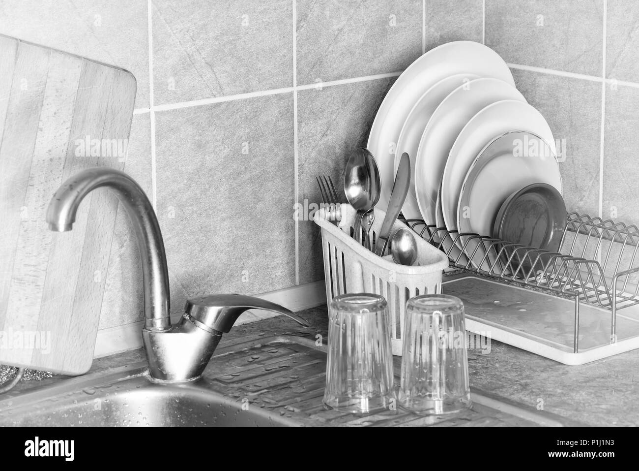 Lavare piatti, posate e bicchieri, essiccazione nel loro rastrelliere vicino al lavello in cucina Foto Stock