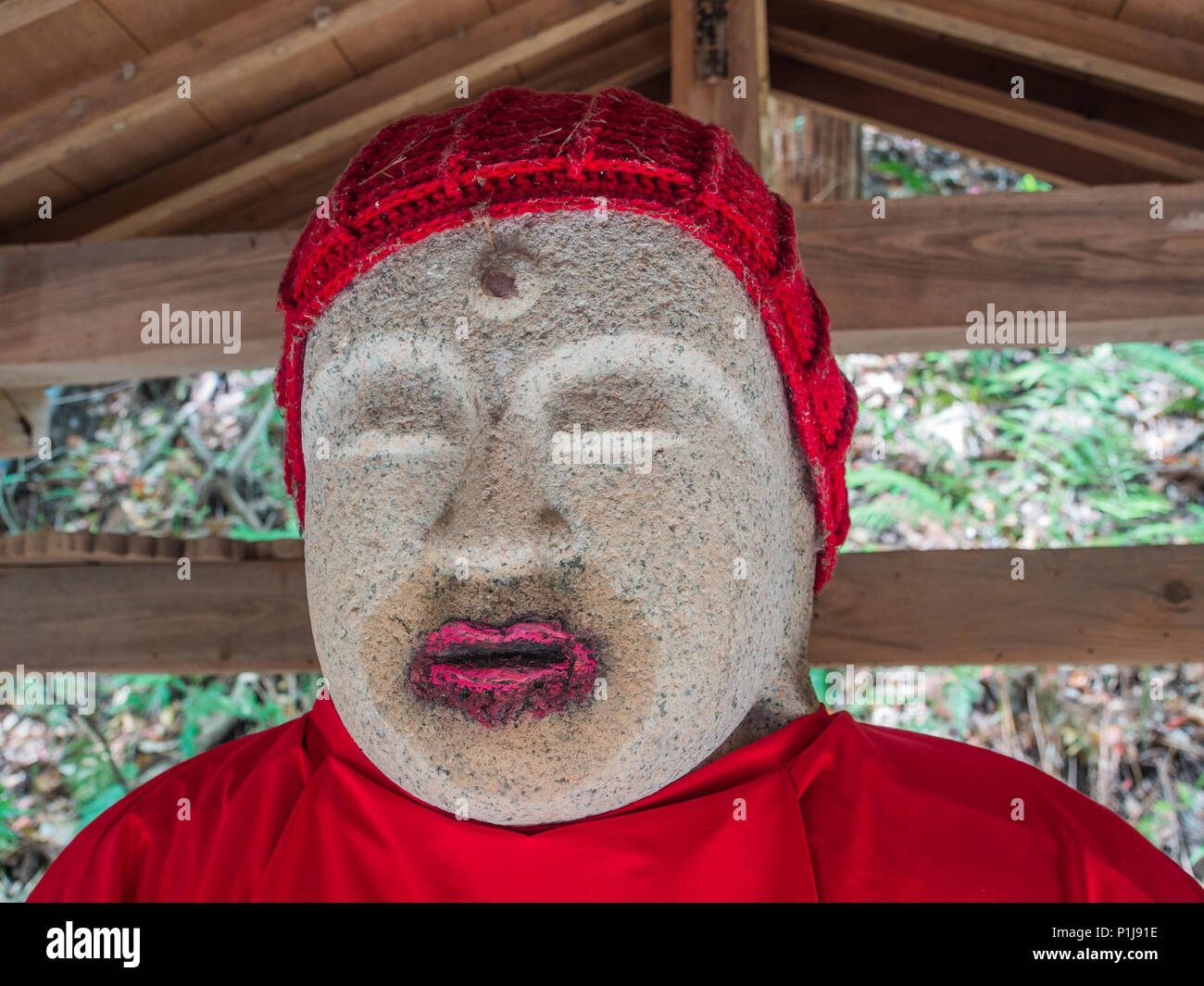 Rossetto sui Jizo Bosatsu statua con red bib e cappuccio rosso, tempio Taisanji 52, Shikoku 88 Ehime, Giappone. Foto Stock