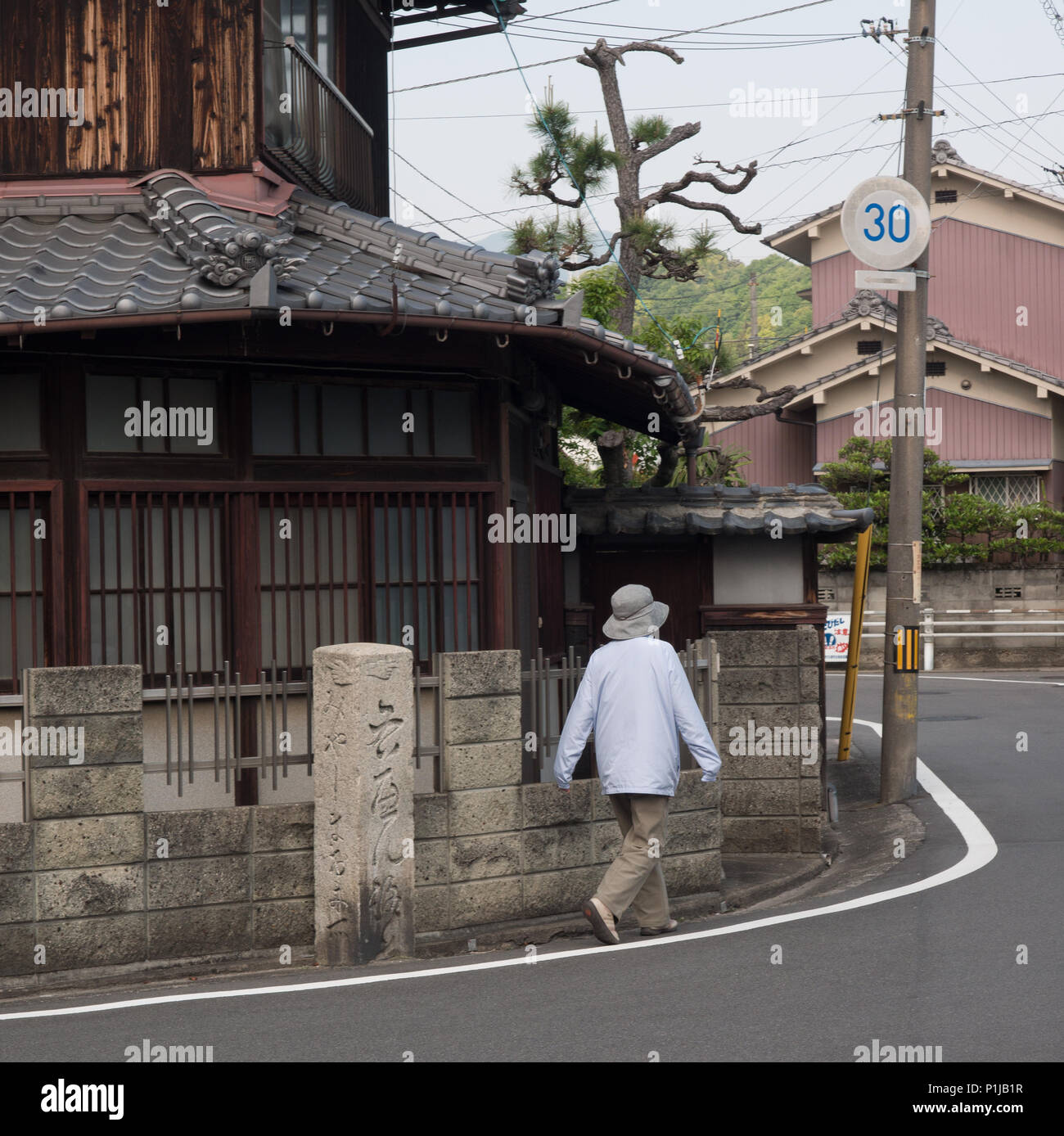 Donna cammina intorno all angolo della strada, con il dito post, guida del percorso, henro no Michi sentiero del pellegrino, Shikoku 88 tempio sentiero del pellegrino, Ehime Giappone Foto Stock