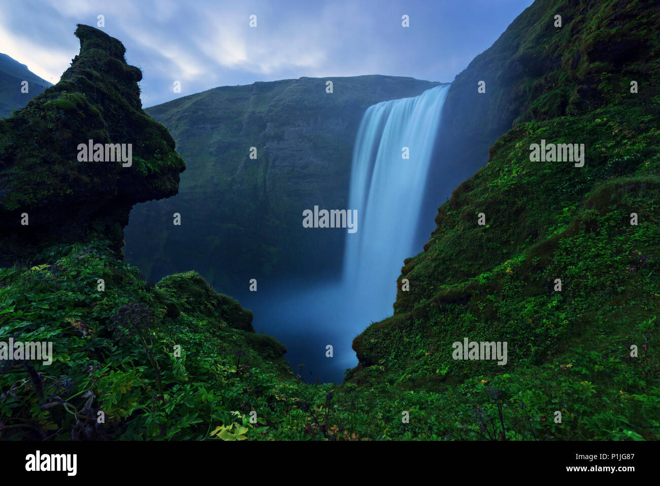 Skogafoss con facce di pietra dopo il tramonto, Islanda Foto Stock