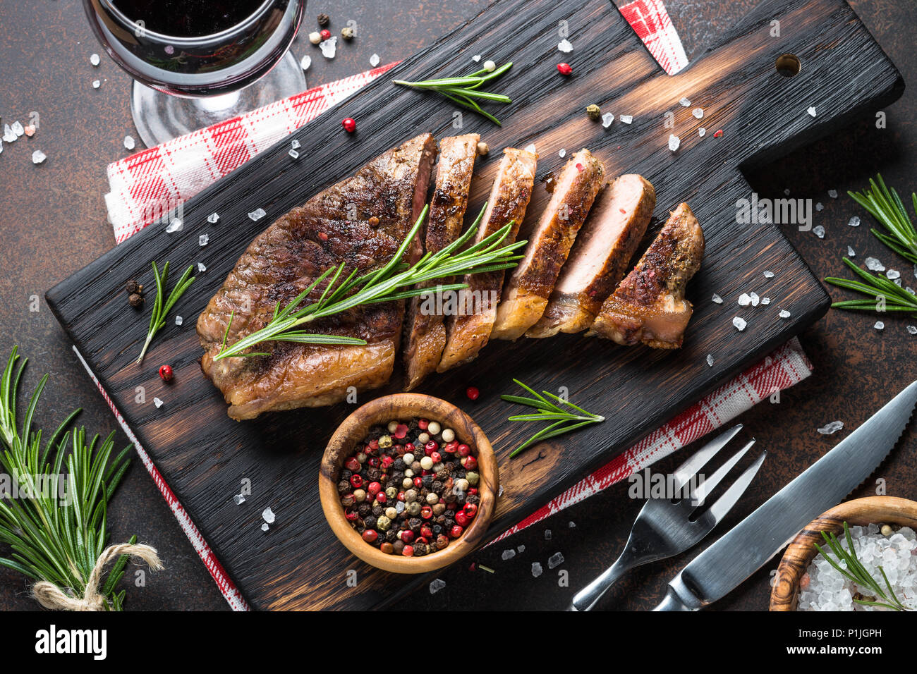 Grigliate di carne di manzo bistecca di controfiletto con vino rosso in vetro. Vista dall'alto sulla pietra scuro dello sfondo. Foto Stock