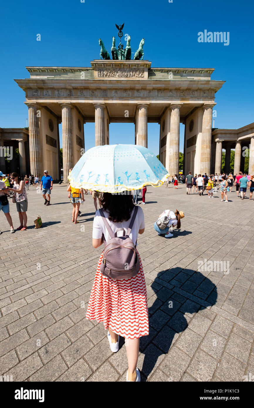 Turisti cinesi con sun parasol nella parte anteriore della porta di Brandeburgo a Berlino, Germania Foto Stock