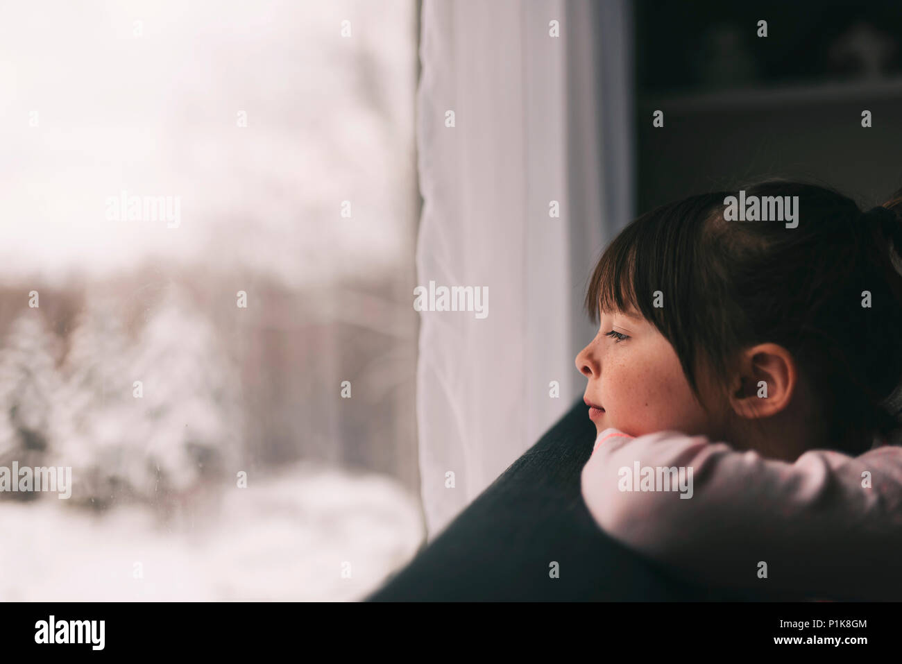 Ragazza guardando fuori della finestra in inverno Foto Stock