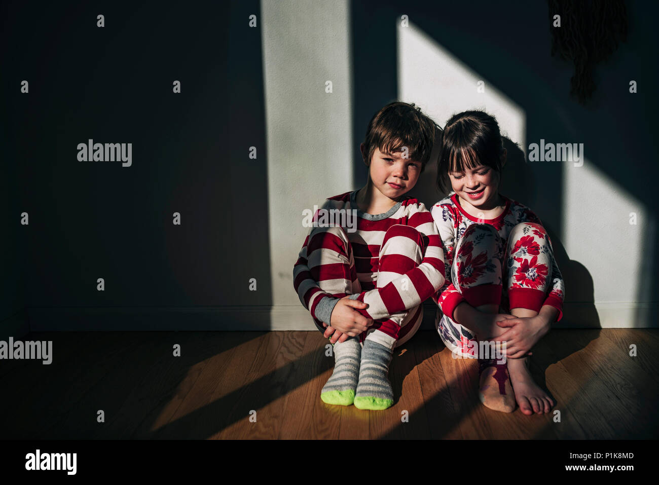 Fratello e Sorella seduta sul pavimento in pigiama Foto Stock