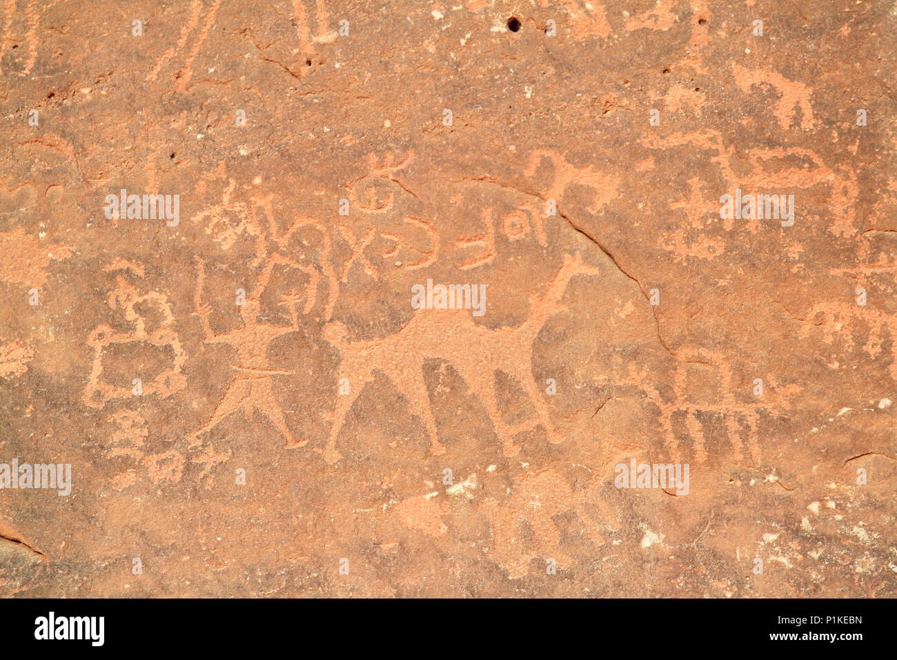 Immagini di persone e cammelli scavata in una parete di roccia a Wadi Rum, un sito Patrimonio Mondiale dell'UNESCO in Giordania. Foto Stock