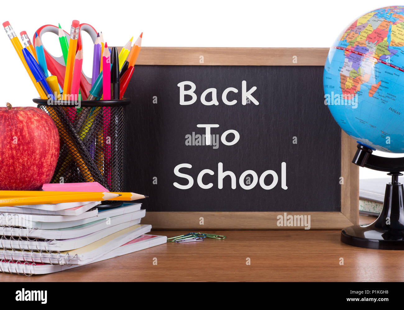 "Si torna a scuola" testo scritto su una lavagna con la scuola accessori su una scrivania in legno e uno sfondo bianco Foto Stock