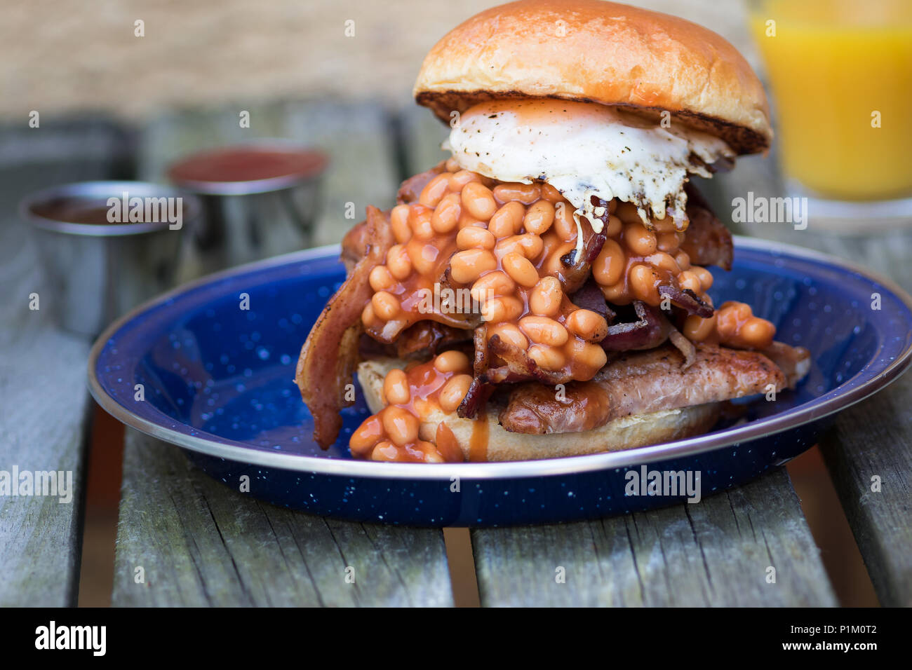 Salsicce,l'uovo,pancetta e fagioli al forno servito in una brioche bun per la prima colazione Foto Stock