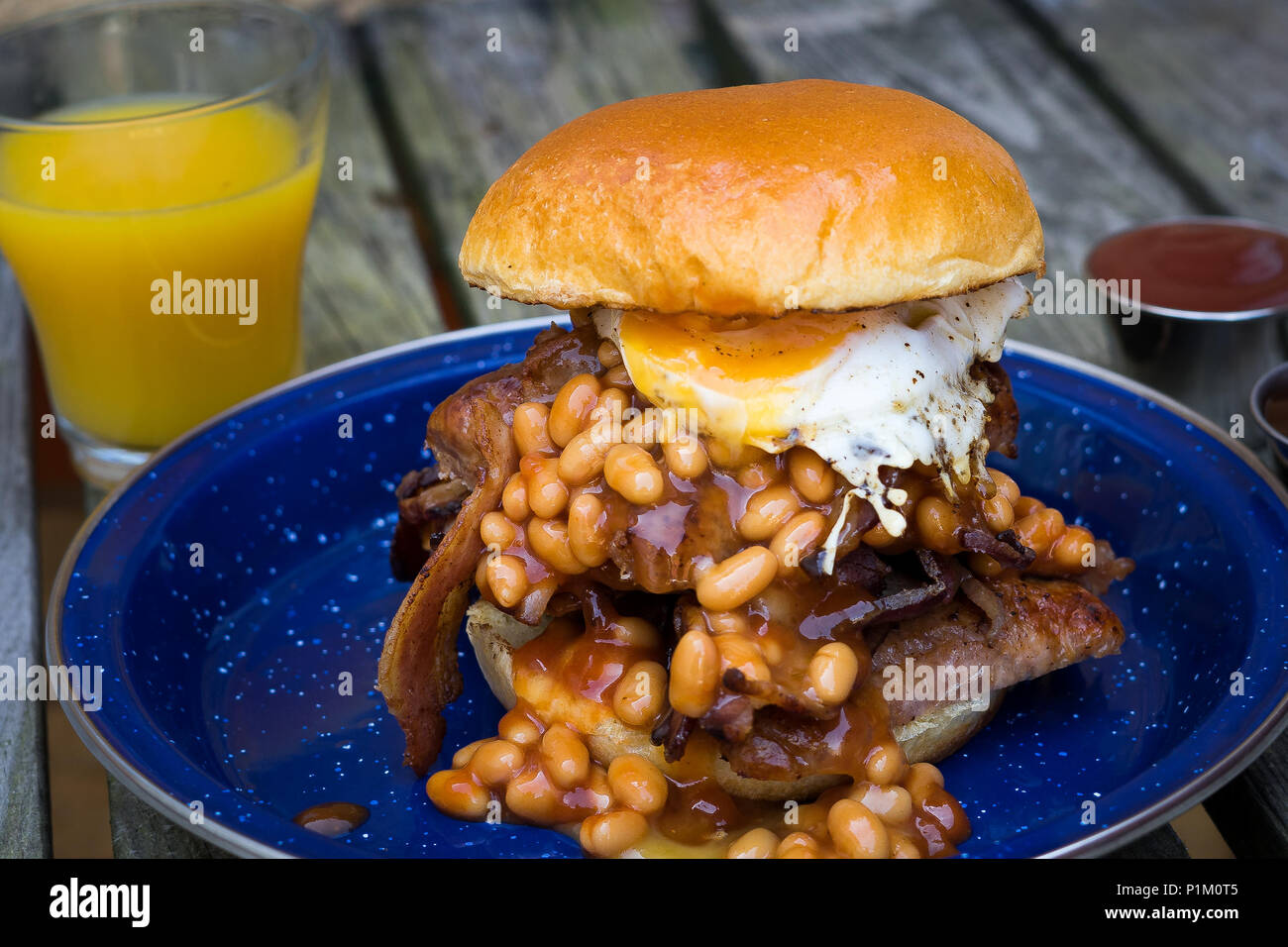 Salsicce,l'uovo,pancetta e fagioli al forno servito in una brioche bun per la prima colazione Foto Stock