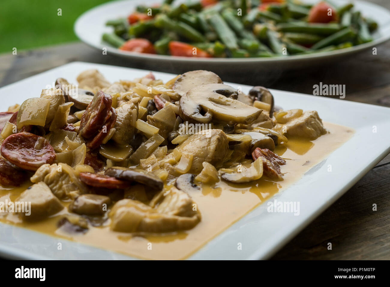 Il pollo e il Chorizo in una salsa di brandy con un lato di fagioli francesi e i pomodorini Foto Stock