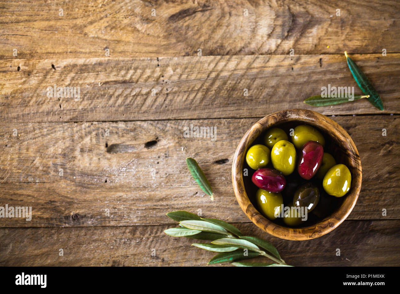 Le olive sul ramo di olivo. Tavolo in legno con le olive in un recipiente Foto Stock