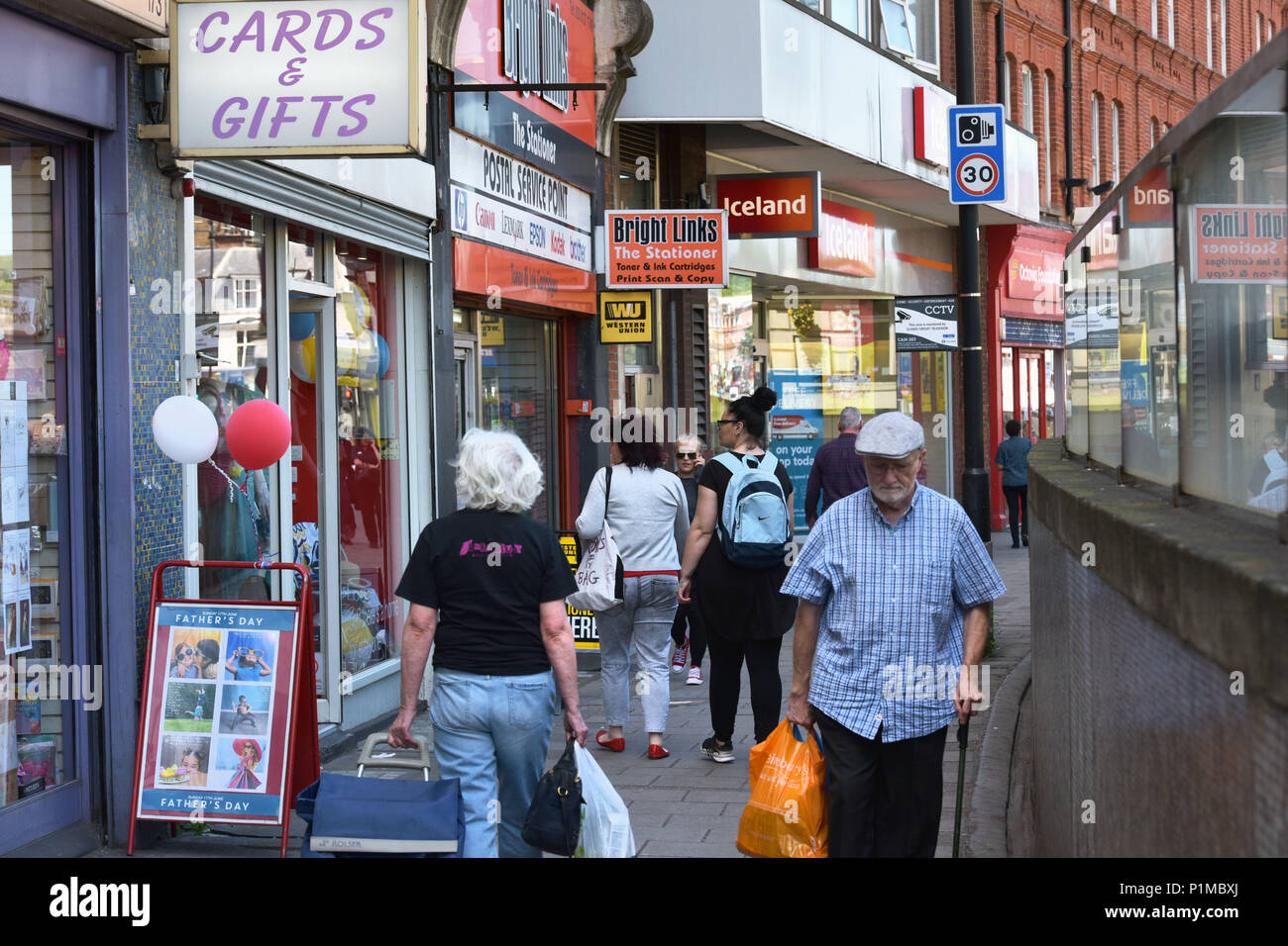 Le persone e gli amanti dello shopping a piedi passato indipendenti e negozi di beneficenza ed un ramo di Islanda, situato sulla Finchley Road High Street a Londra del nord. Foto Stock